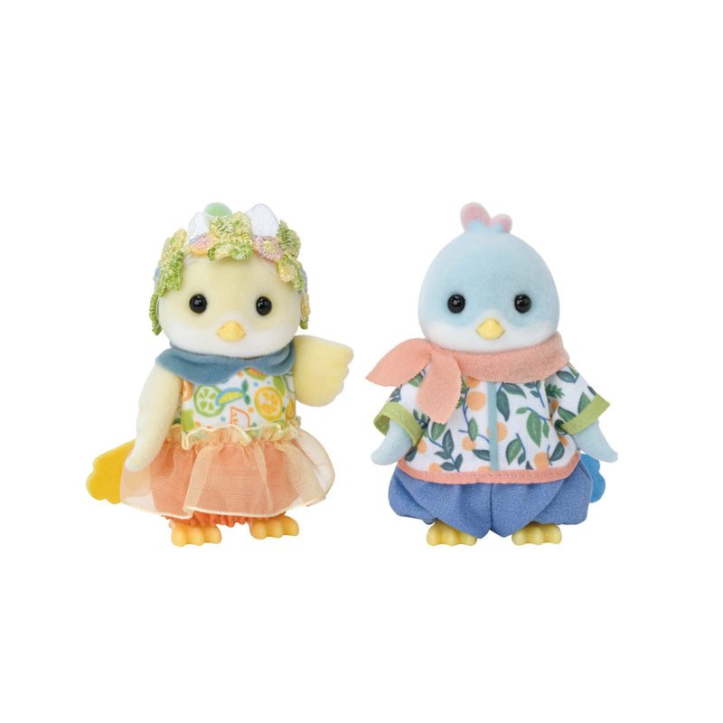 Two cute penguin plush toys in colorful outfits on white background