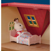 Red roof dollhouse cottage interior with rabbit figure in bed under sloped ceiling