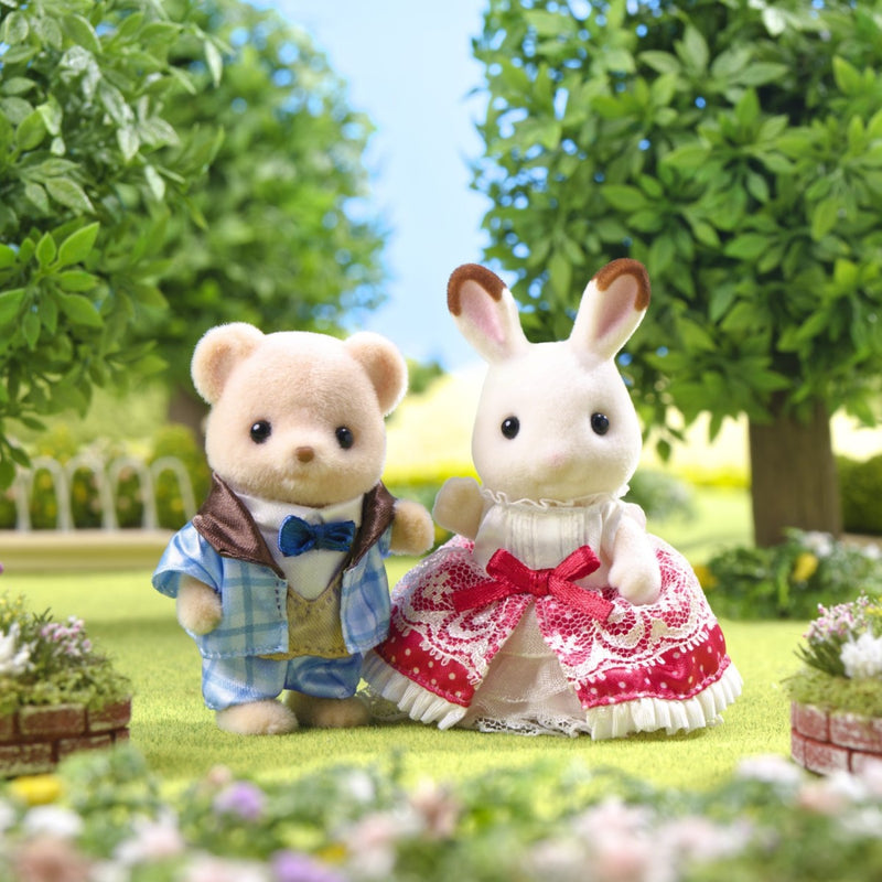Two Sylvanian Families figures - bear in blue outfit and rabbit in red dress in garden setting