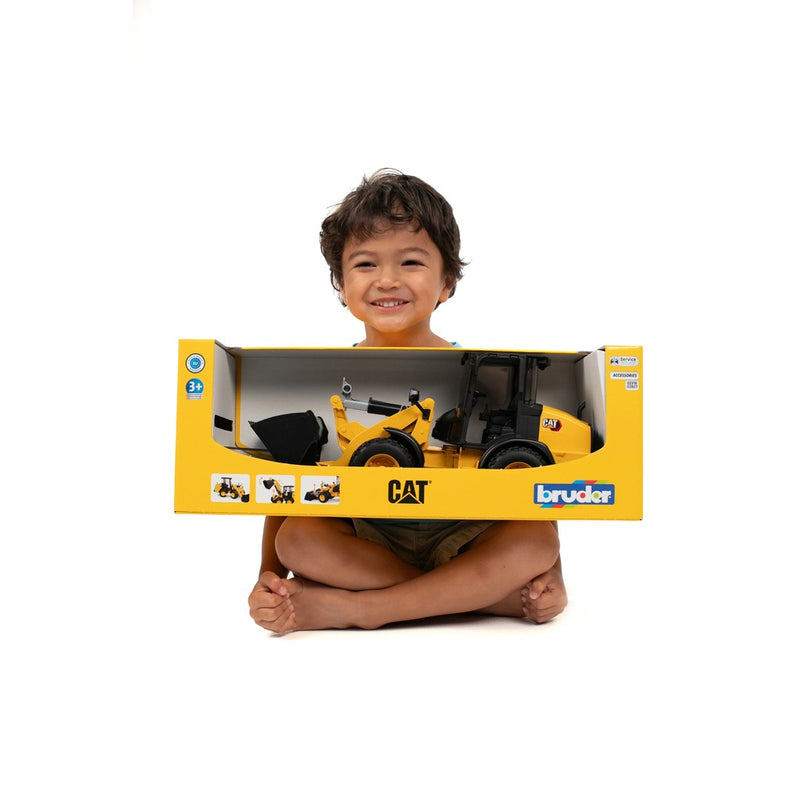Happy child holding CAT Wheel Loader toy in Bruder packaging box