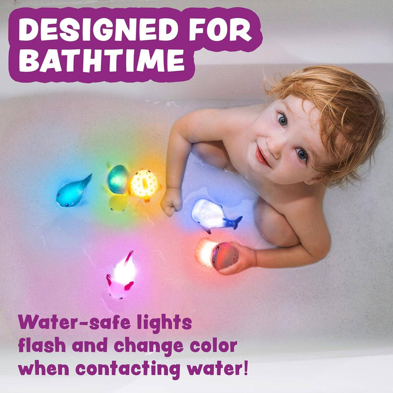 Child playing with colorful light-up ocean themed bath toys in bathtub
