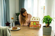 Woman enjoying assembled Ravensburger 3D gingerbread house puzzle at home table