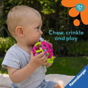 Baby chewing on Ravensburger colorful lattice ball sensory teething toy outdoors
