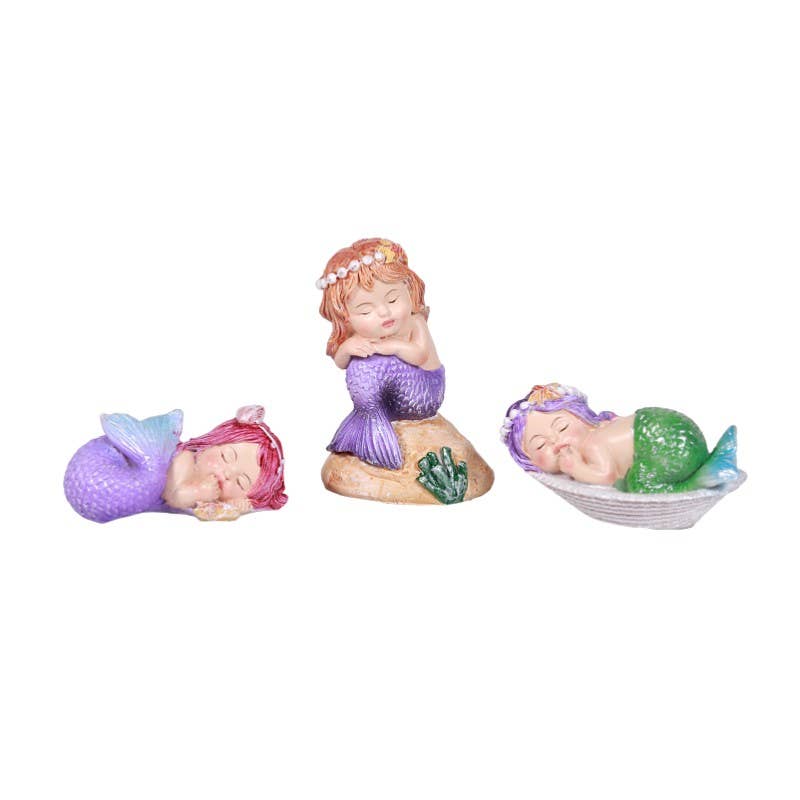Three small decorative mermaid figurines in purple and green tails on white background