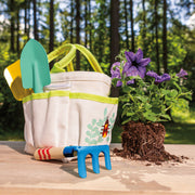 Garden tote kit with tools and flowering plant on wooden surface outdoors