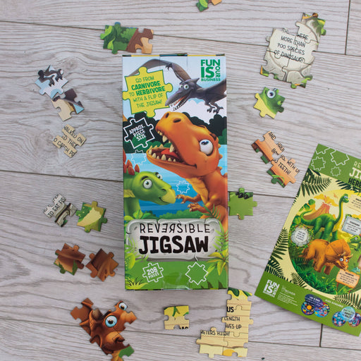 Dinosaur reversible jigsaw puzzle with scattered pieces showing carnivore to herbivore theme