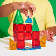 Child playing with colorful magnetic building tiles creating castle structure