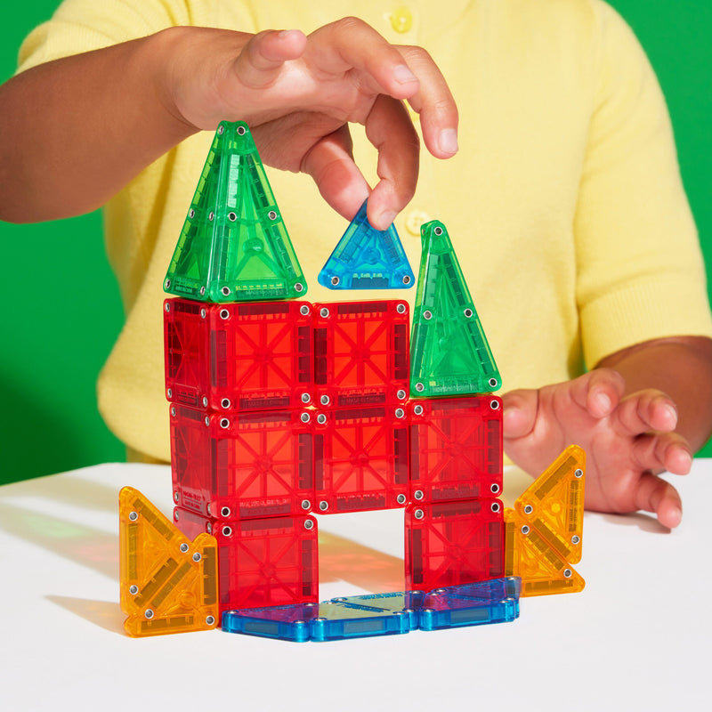 Child playing with colorful magnetic building tiles creating castle structure