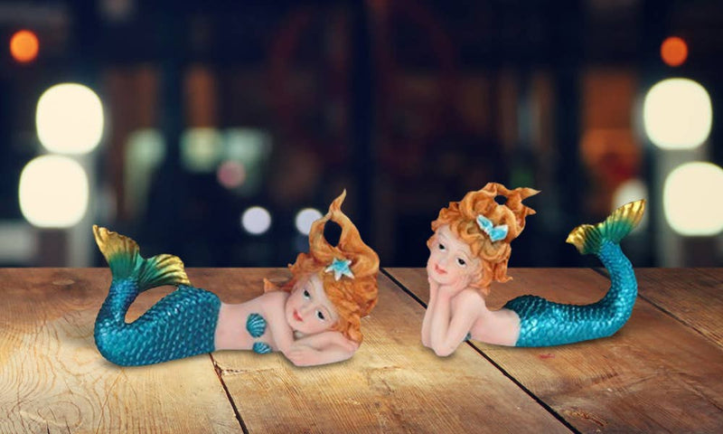Two decorative mini mermaid figurines with teal tails on wooden surface