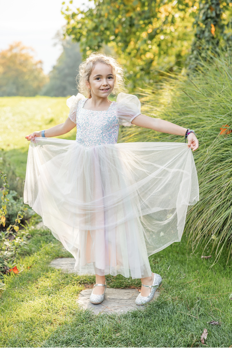 Young girl wearing sparkly rainbow tulle dress in garden setting