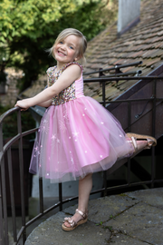 Young girl wearing pink sequined dress with tulle skirt and star decorations
