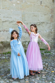 Two girls in princess costumes dancing against stone wall background