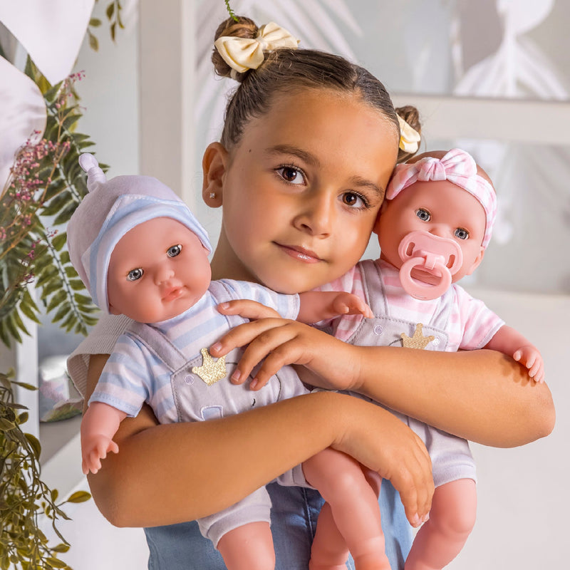 Child holding two Berenguer 15 inch twin baby dolls in striped outfits
