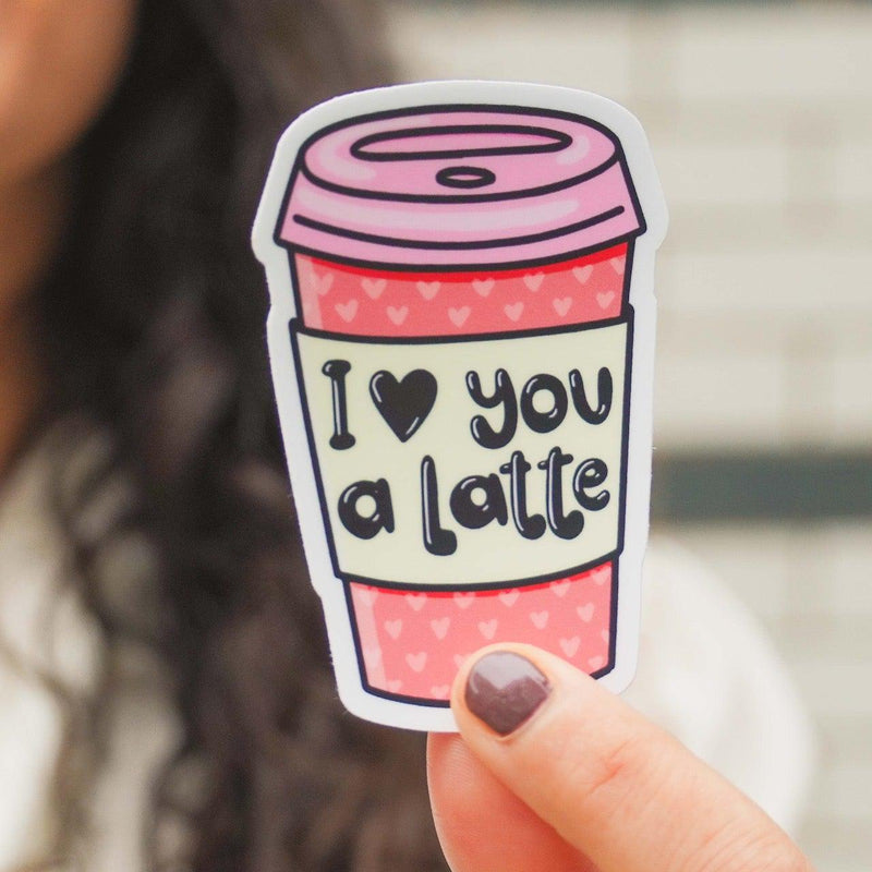 Hand holding pink coffee cup vinyl sticker with 'I love you a latte' text