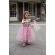 Young girl wearing pink sequined dress with tulle skirt and star wand outdoors