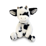 Black and white spotted cow plushie toy with horns and large ears sitting upright