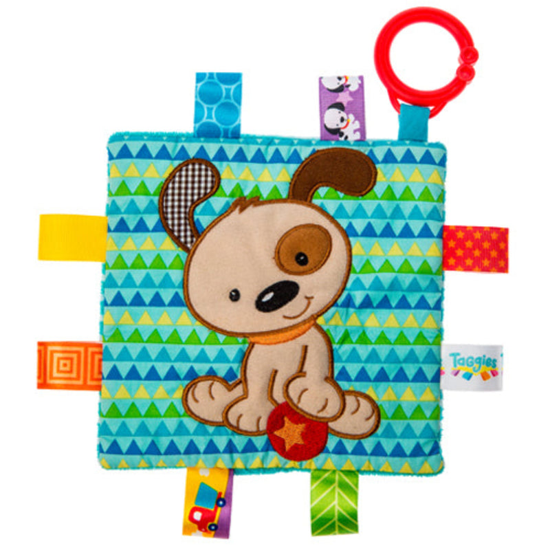 Taggies crinkle toy with puppy design on teal patterned fabric with colorful ribbon tags.