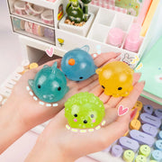 Four colorful glitter mochi squishy toys held in hands on kawaii desk setup