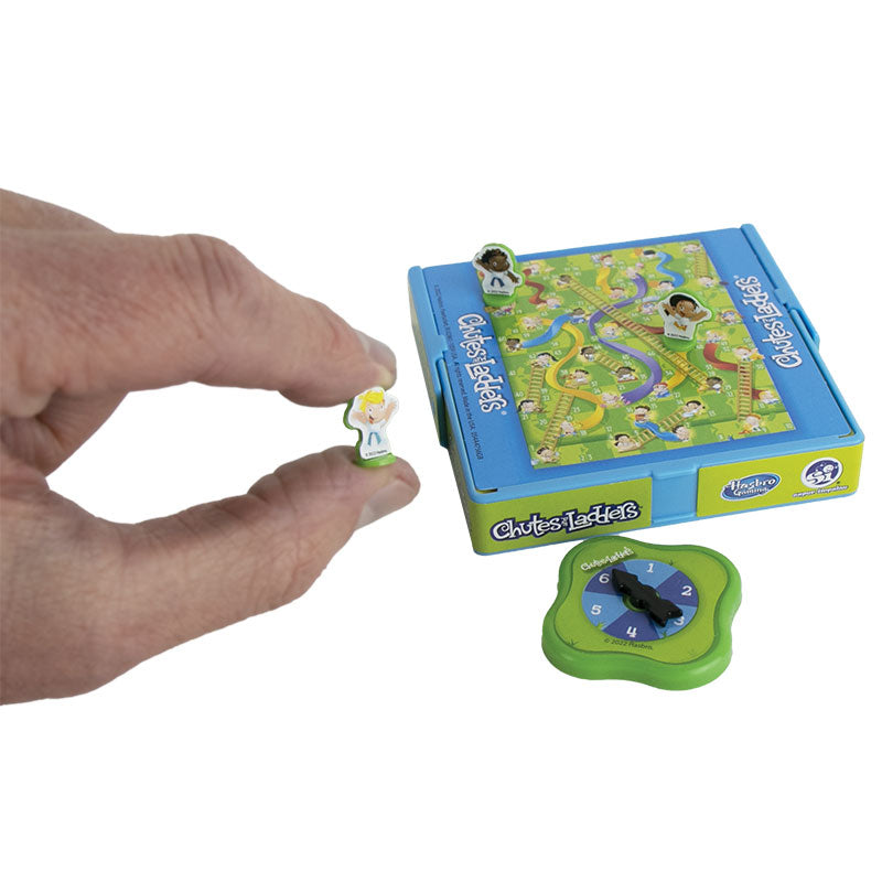 Hand holding miniature game piece next to World's Smallest Chutes and Ladders game box