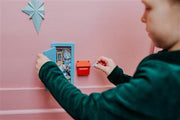 Child playing with blue little mouse door furniture kit on pink wall