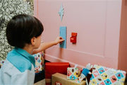Child using Little Mouse Door furniture kit with blue door on pink wall