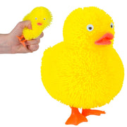 Yellow fuzzy rubber duck squishy toy with orange beak and feet, hand holding smaller version