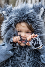Child wearing gray furry wolf costume with hood and paw print gloves