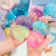 Four glittery squishy seashells in purple, blue, green, and pink held in hands