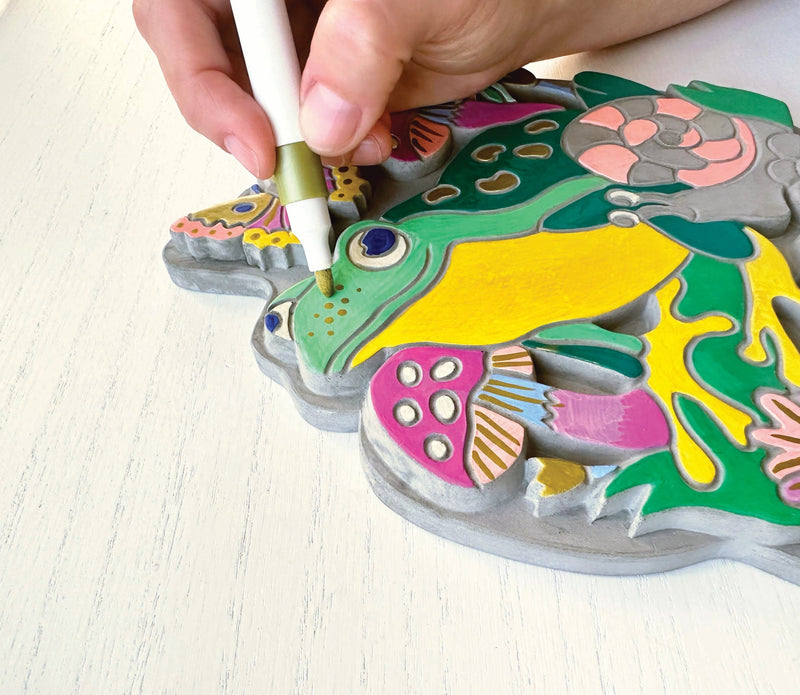 Hand painting colorful garden stone craft with marker showing detailed design