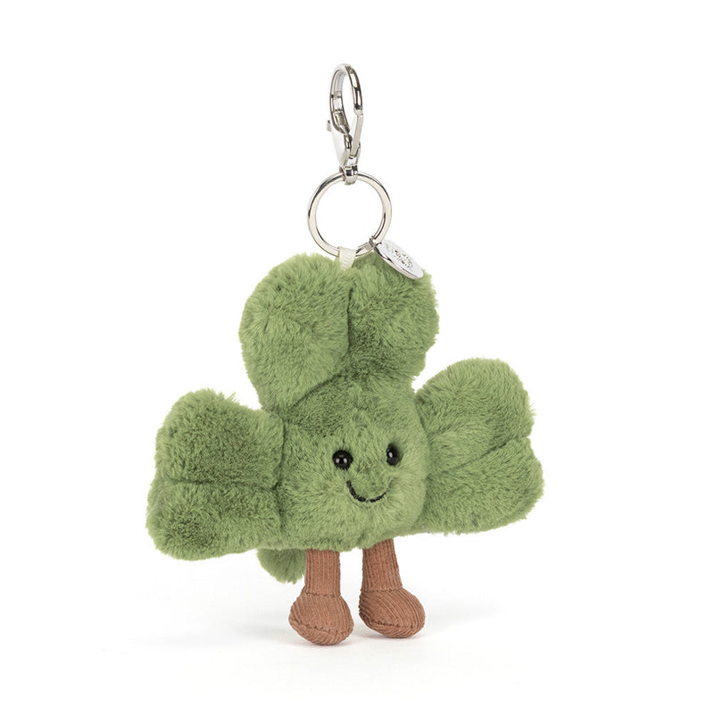Green shamrock plush keychain with smiling face and brown legs on white background