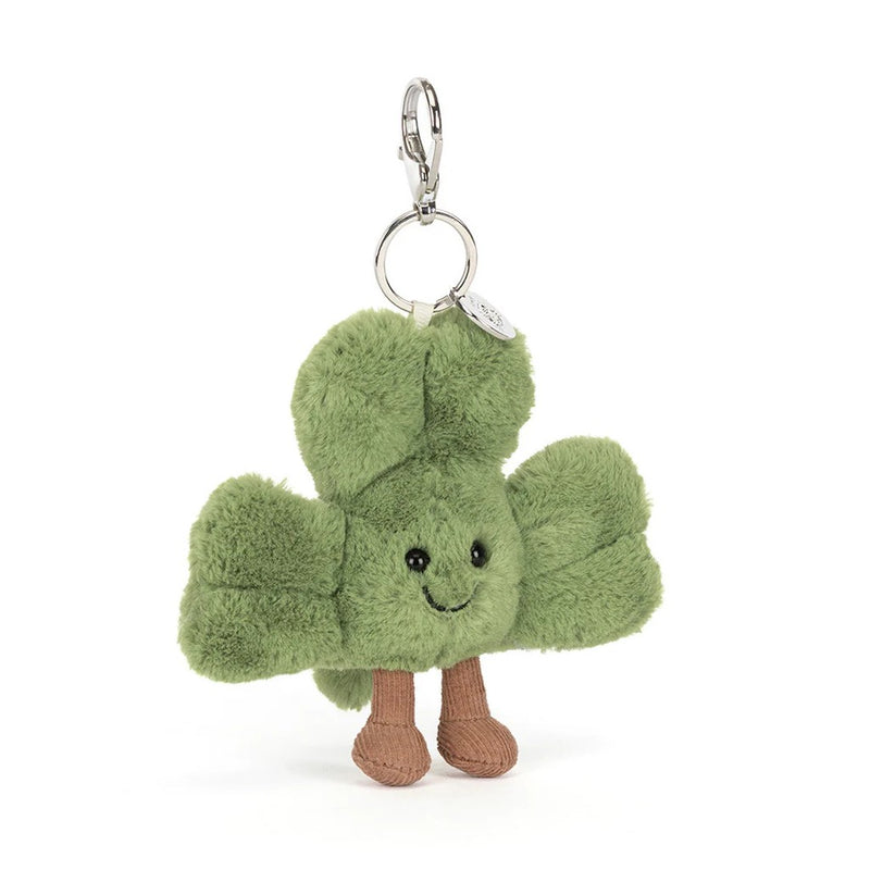 Green shamrock plush keychain with smiling face and brown legs on white background