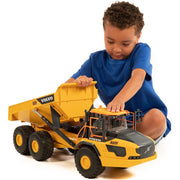 Young boy playing with large yellow Volvo A60H articulated hauler toy truck