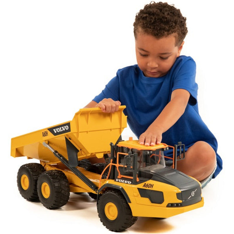 Young boy playing with large yellow Volvo A60H articulated hauler toy truck