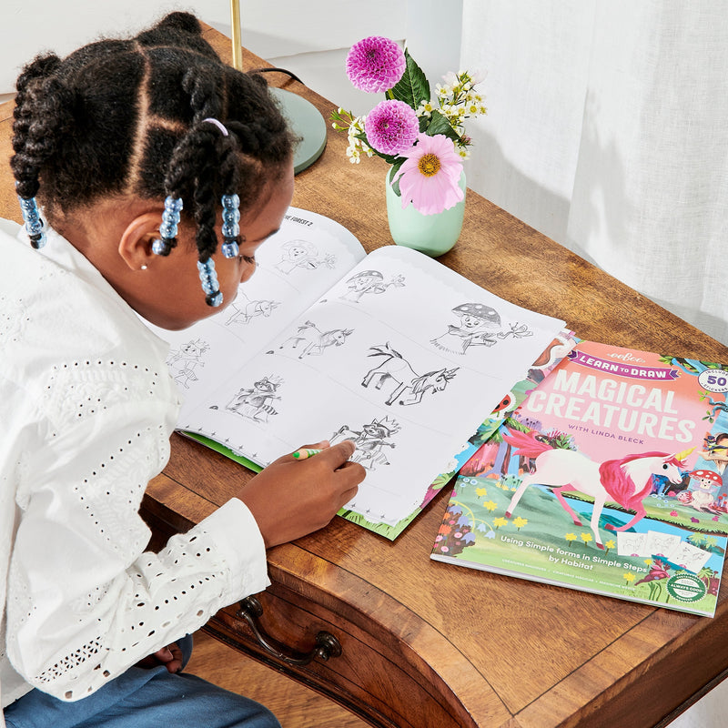 Child drawing magical creatures from eeBoo learn to draw activity book with stickers