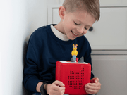 Child using red Toniebox audio player with yellow Arthur character figurine on top
