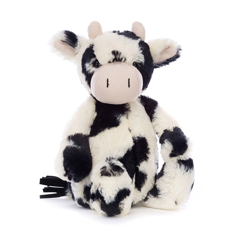 Black and white spotted plush cow stuffed animal sitting on white background