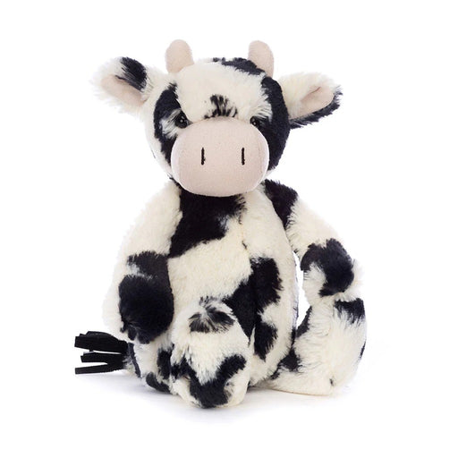 Black and white spotted plush cow stuffed animal sitting on white background