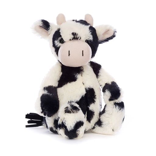 Black and white spotted plush cow stuffed animal sitting on white background