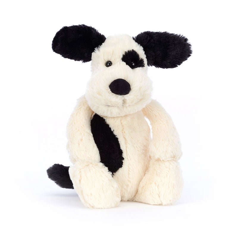 Cream colored stuffed puppy toy with black ears and eye patch on white background
