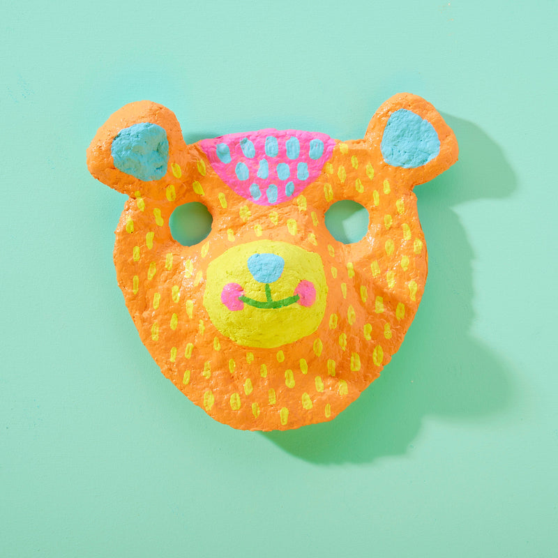 Colorful orange paper mache bear mask with painted decorative patterns and ears