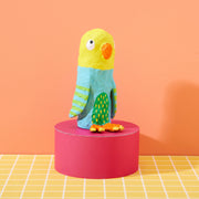 Colorful paper mache parrot craft with yellow head and blue body on red platform