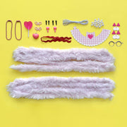 DIY craft kit components including pink fur strips and cat-themed accessories on yellow background