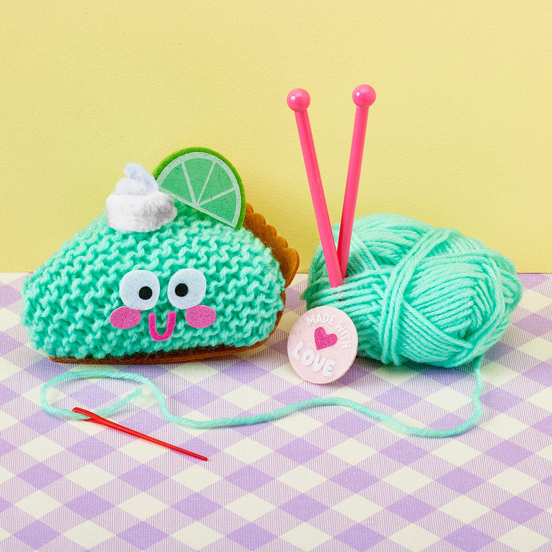 Key lime pie knit kit with green yarn ball, pink needles, and taco plushie