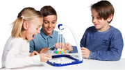 Three children sitting at a white table playing with a blue and white pendulum toy with colorful hanging balls.