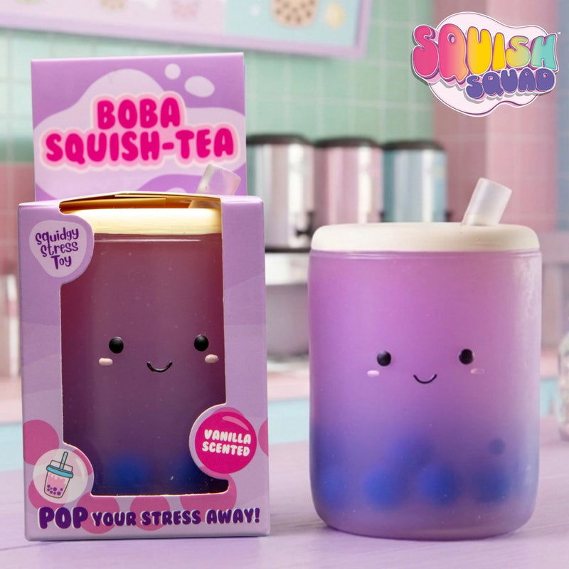 A purple and blue gradient boba tea cup with a cute smiling face next to its pink packaging box. The box features the text 'BOBA SQUISH-TEA' and 'Shiny Stress Toy'.