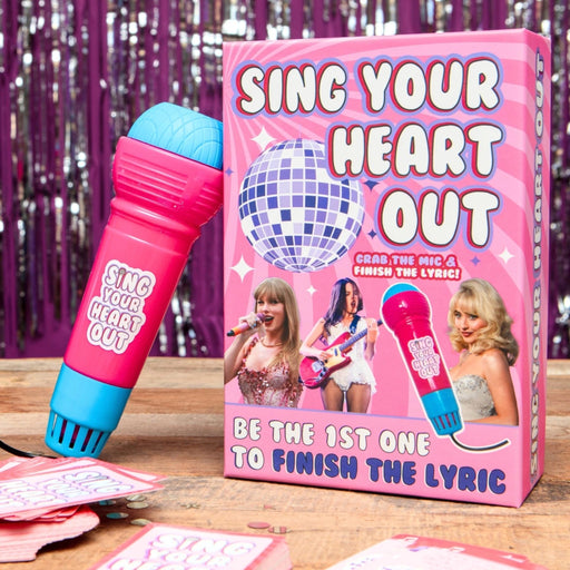 Game box for 'Sing Your Heart Out' with a microphone and disco ball on a wooden surface.