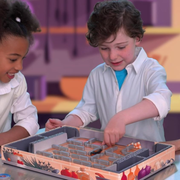 Two children playing Bugs in the Kitchen in a colorful room.