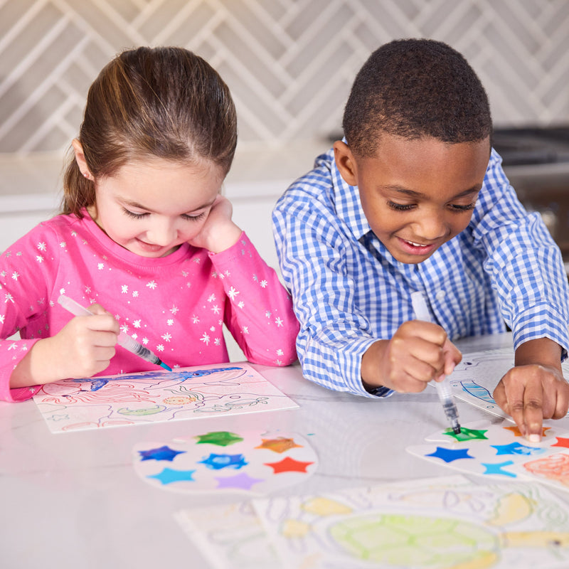 Two children using Magic Watercolor Ocean Adventure coloring activity with star stickers
