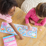 Two children playing with Crocodile Creek Magnetic Rainbow Race board game on wooden floor.