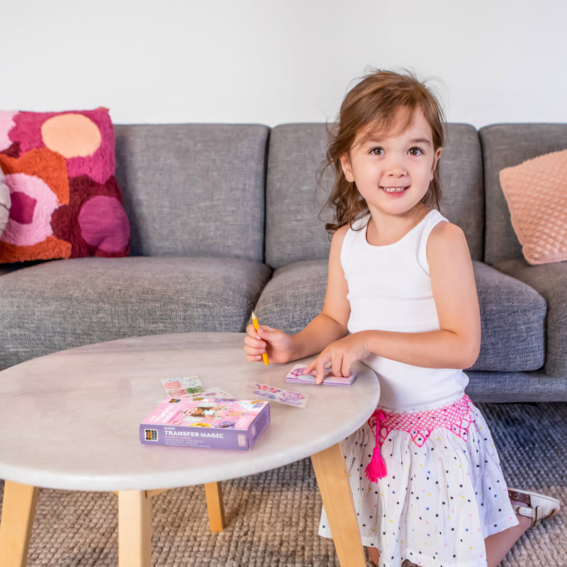 Young girl using Tiger Tribe Mini Transfer Magic Flower Fairies activity set at coffee table